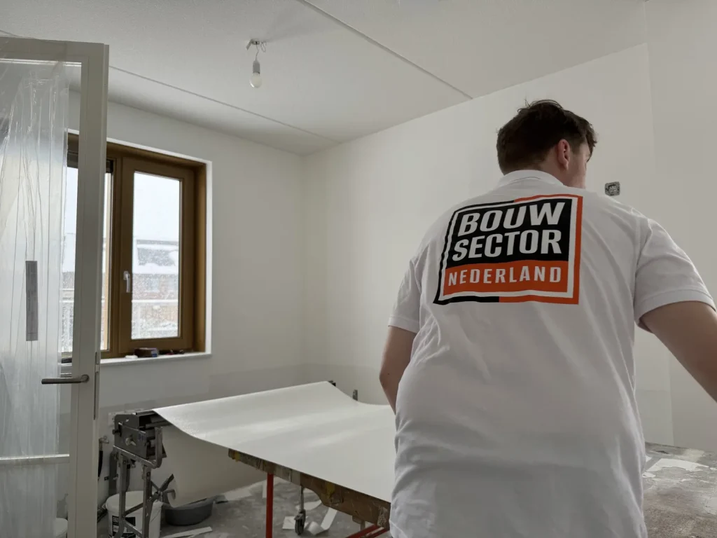 Behanger van Bouwsector Nederland rolt een baan renovlies uit over de plaktafel