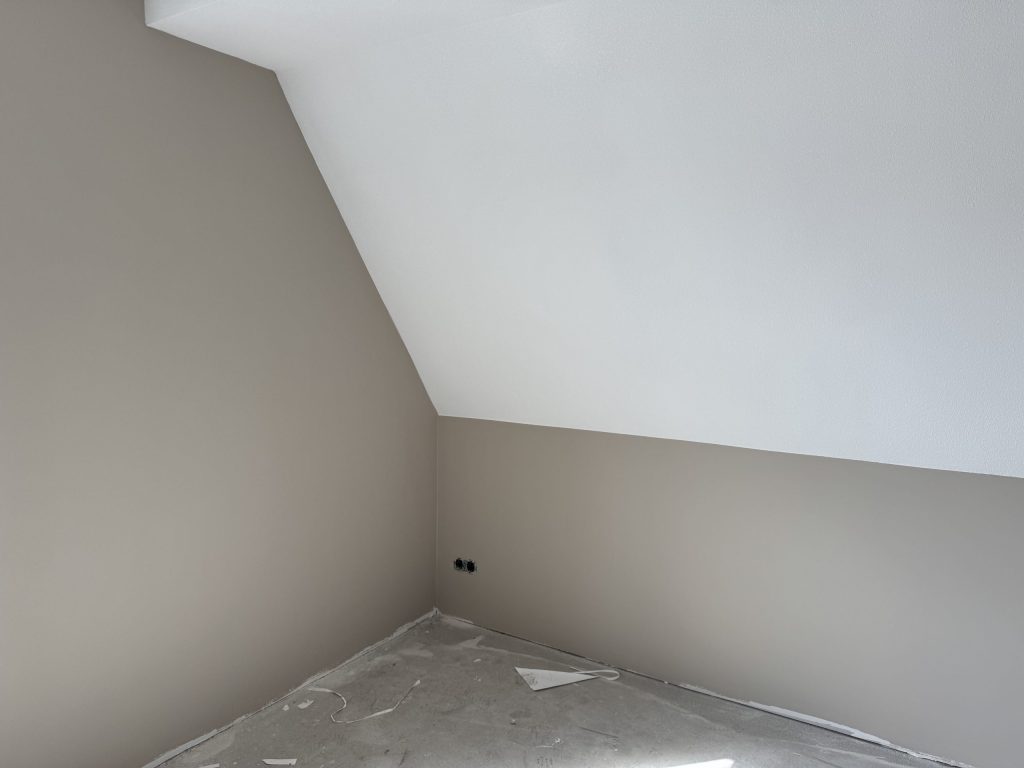 Zolderkamer met een schuine wand en afgewerkte wanden in een lichte grijstint